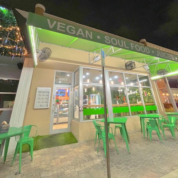 C4Eats vegan restaurant exterior at night with green awning, outdoor seating, and illuminated sign.